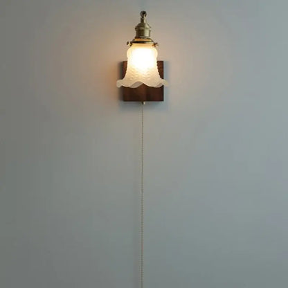 Brass walnut wood wall sconce with brass-finished metal and off-white textured glass shade on dark wood plate decorbites brass walnut