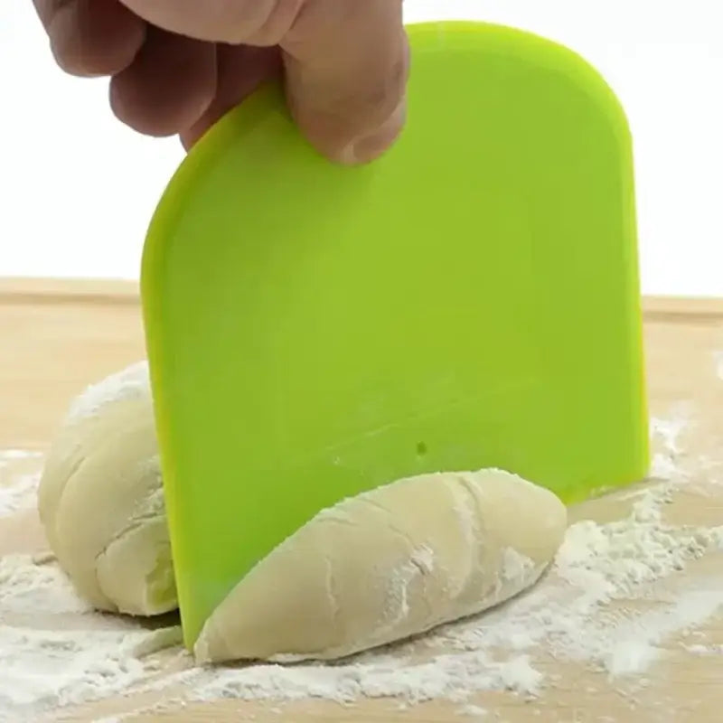 Bright green silicone spatula dough cutter being used to portion dough as a decorbites cake spatula dough tool