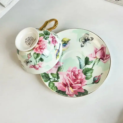 Delicate porcelain teacup and saucer set with brilliant flowers pattern of pink roses green leaves and gold accents
