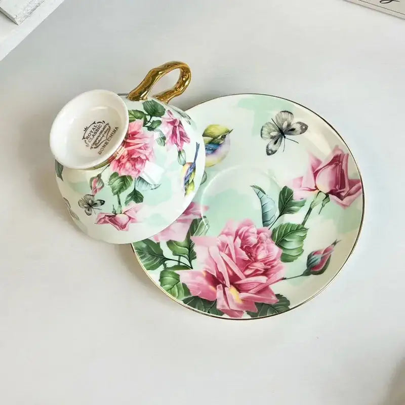 Delicate porcelain teacup and saucer set with brilliant flowers pattern of pink roses green leaves and gold accents
