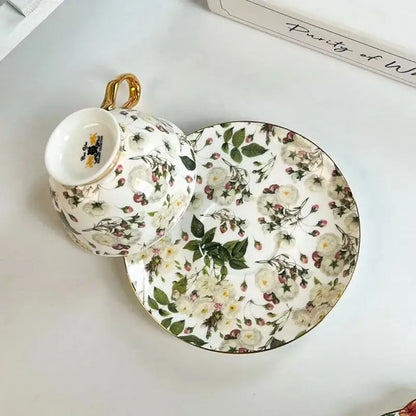 White porcelain teacup and saucer dining set with brilliant flowers pattern in soft greens, whites, blush pinks, and gold accents