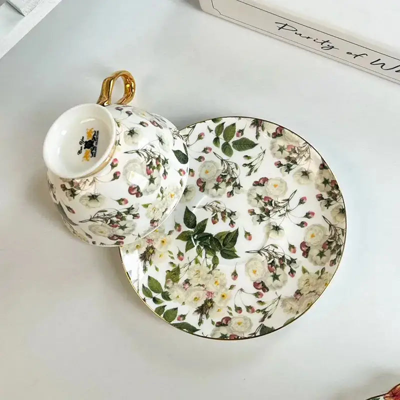 White porcelain teacup and saucer dining set with brilliant flowers pattern in soft greens, whites, blush pinks, and gold accents