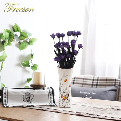 White ceramic bird butterfly porcelain vase with delicate decals holding dried purple roses for living room decorbites decor