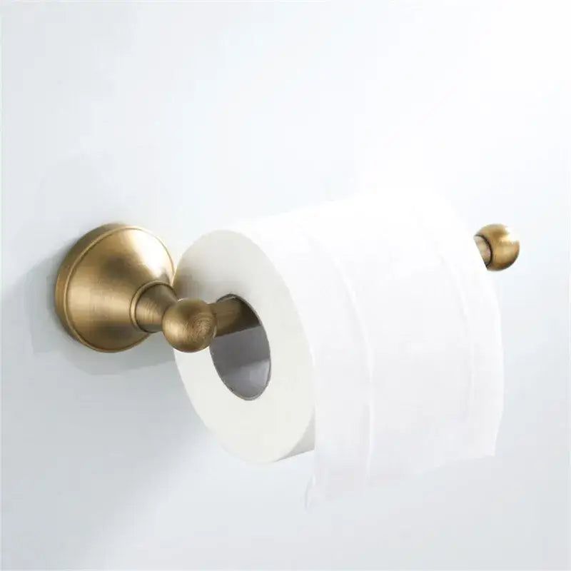 Antique brass toilet paper holder with ornate design holding white roll in decorbites bronze bathroom accessories set