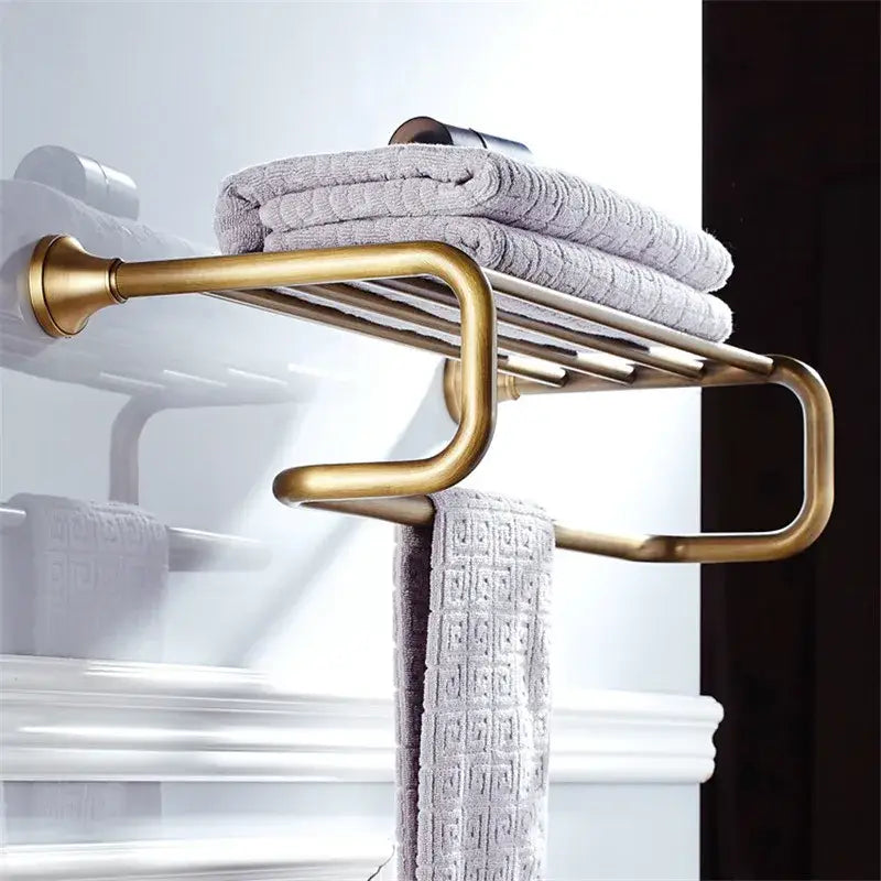 Brass-finished curved multi-tiered towel rack holding gray textured towels in decorbites bronze bathroom accessories set