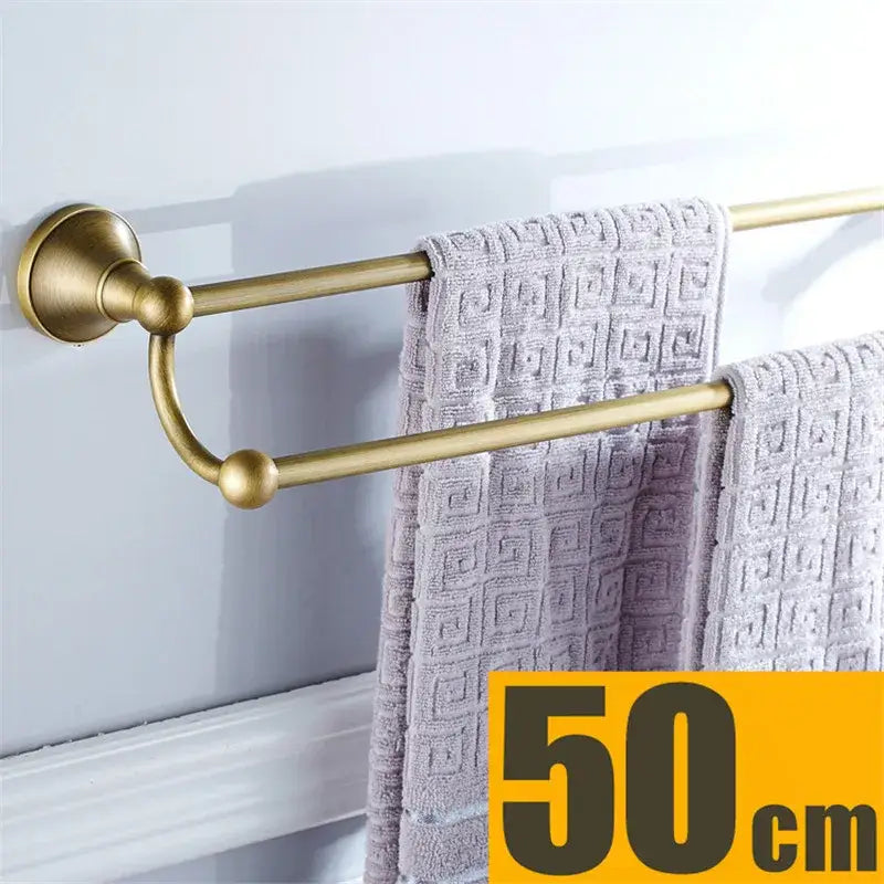 Brass double towel rack with decorative curved connector and light gray towels in decorbites bronze bathroom accessories set