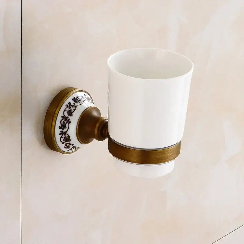 White ceramic toothbrush holder with vintage brass finish and black floral patterns in decorbites bronze bathroom hardware set