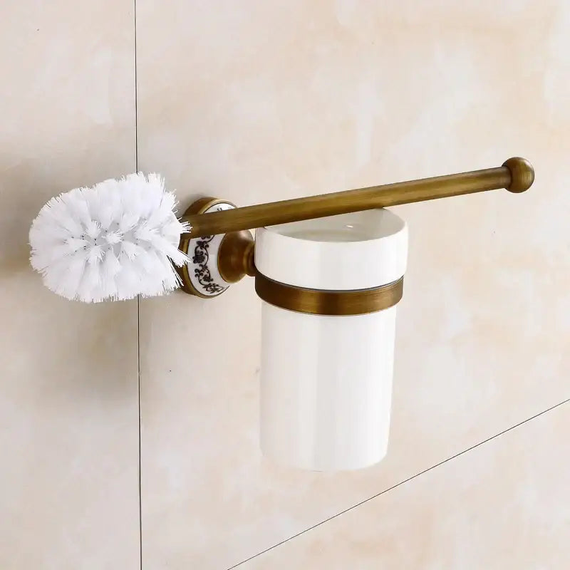 White ceramic toilet brush holder with brass-finished handle and black floral base in decorbites bronze bathroom hardware set