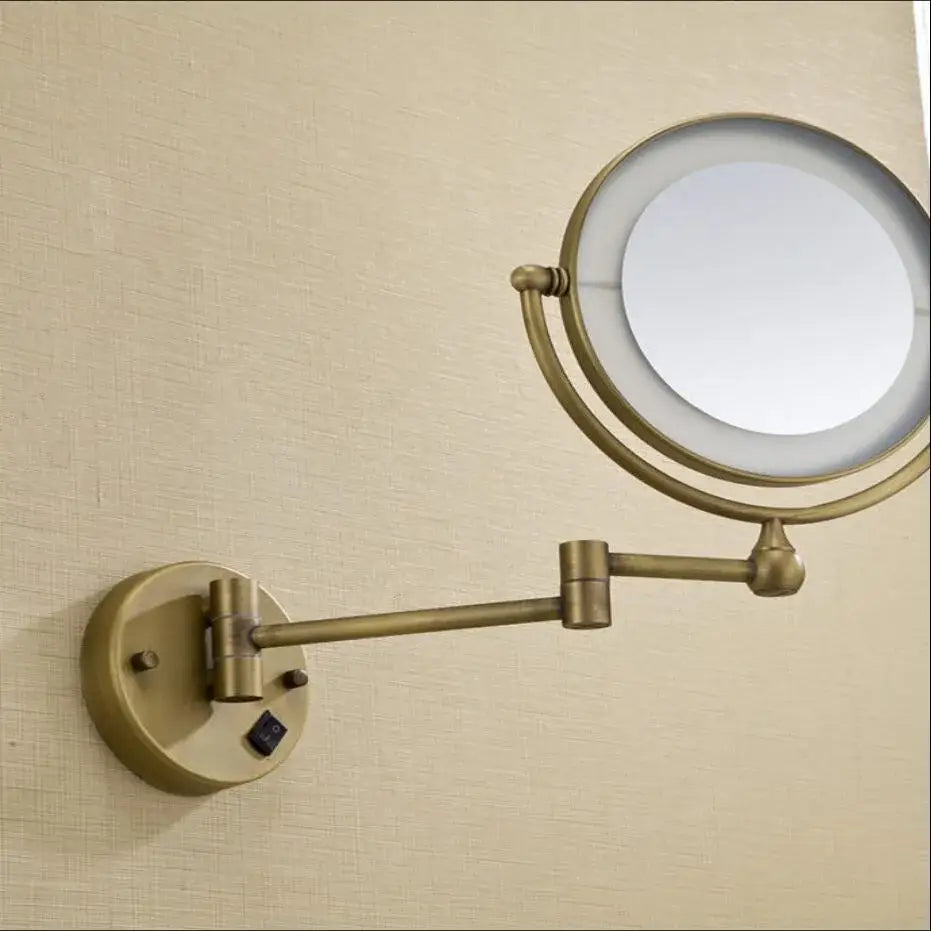 Brass wall mounted illuminated makeup mirror with adjustable arm and bronze brass wall finish for bathroom use