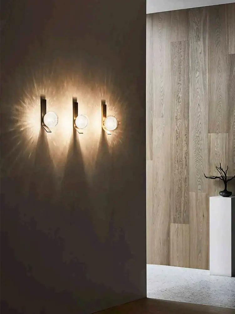 Three bronze bubble glass wall sconce lamps with black metal fixtures emit a warm glow for bedroom use