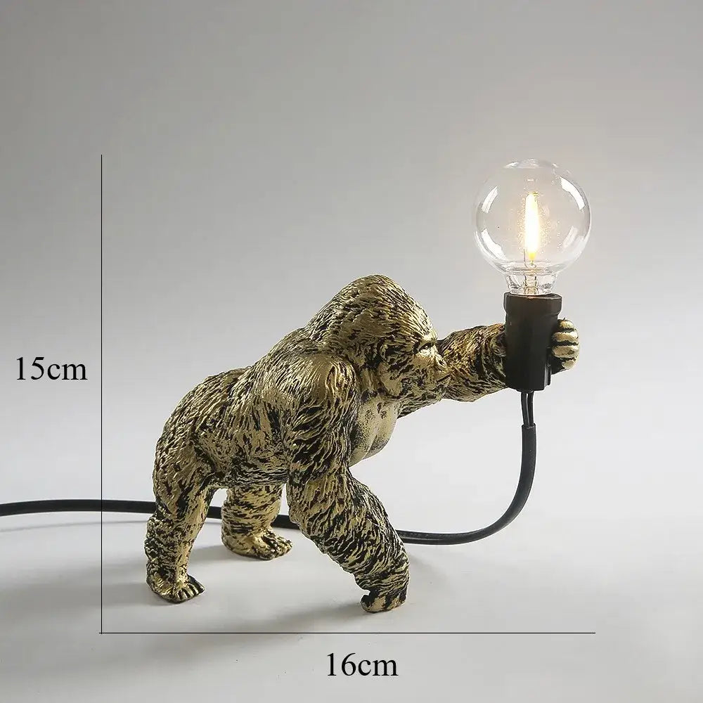 Bronze king kong gorilla table lamp with textured fur detail in gold holding a clear bulb for bedroom night light