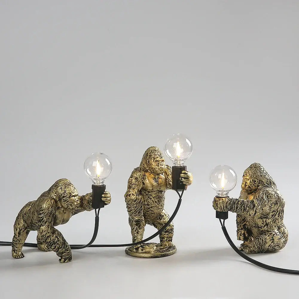 Three golden bronze king kong gorilla table lamps with lit bulbs connected by black cords ideal for bedroom decorbites king kong