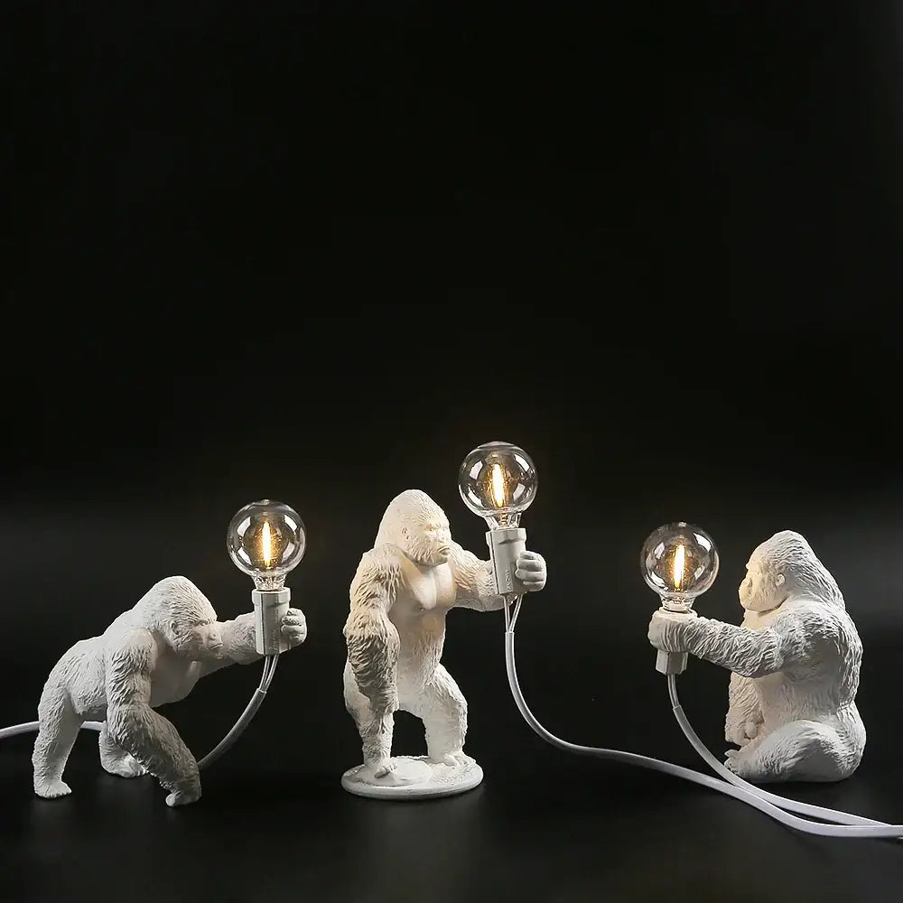 Three white king kong gorilla table lamp figurines holding glowing bulbs connected by cords for decorbites bedroom light