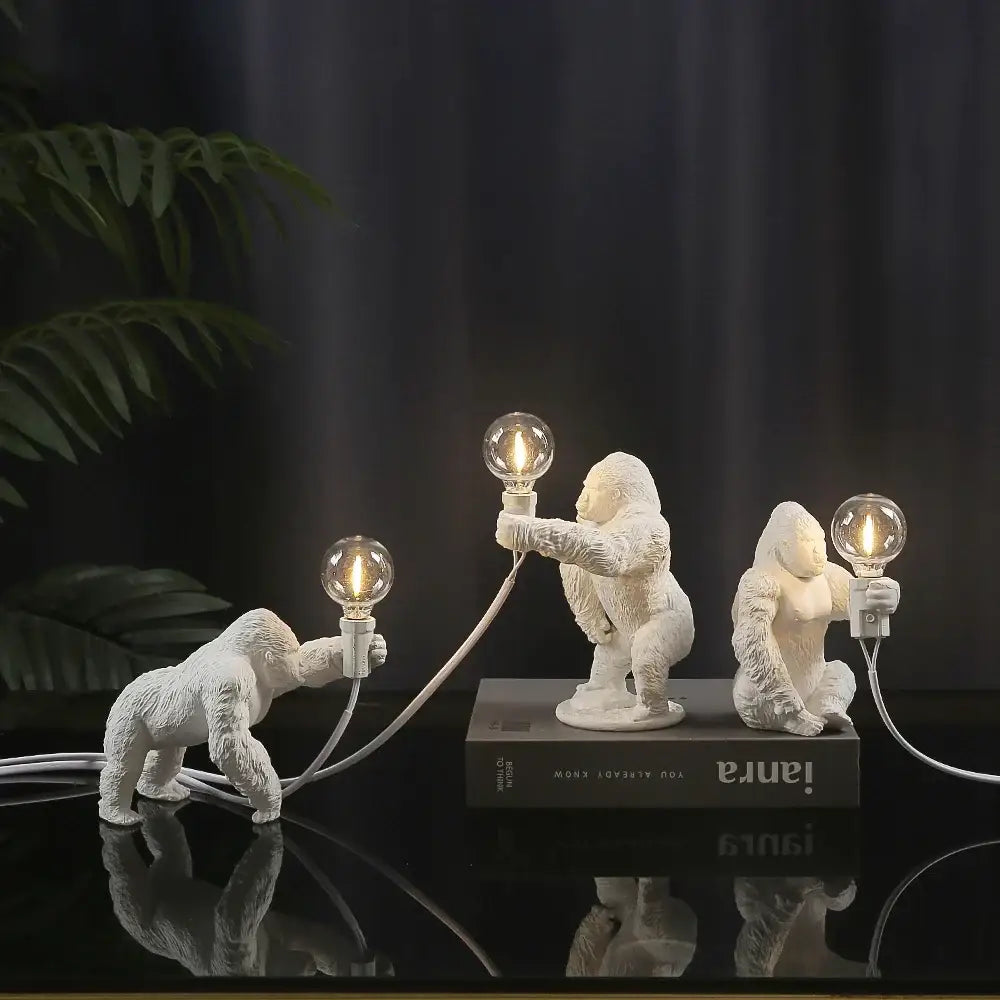 Three white resin king kong gorilla figurines holding lit bulbs connected by cords table lamp decorbites king kong