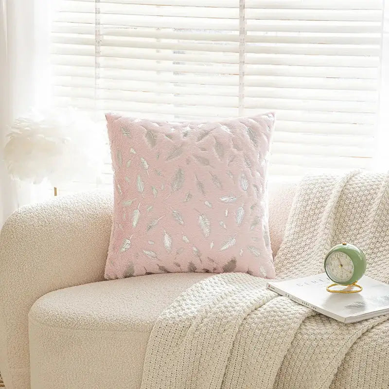 A soft pink quilted cushion with silver feather embroidery complementing bronzed feather style emerald green velvet pillowcase decor