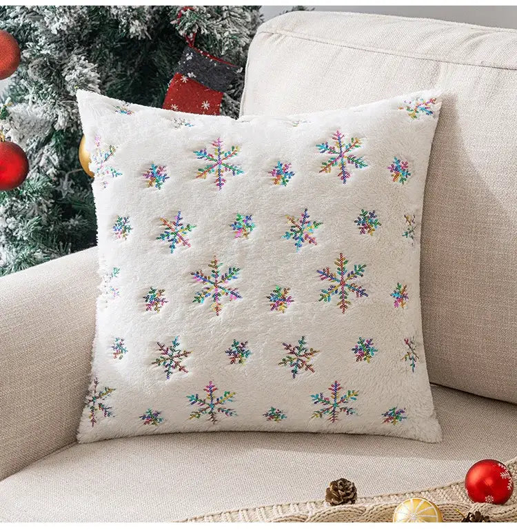 White plush pillow with colorful embroidered snowflakes complementing bronzed feather style emerald green velvet pillowcase decor