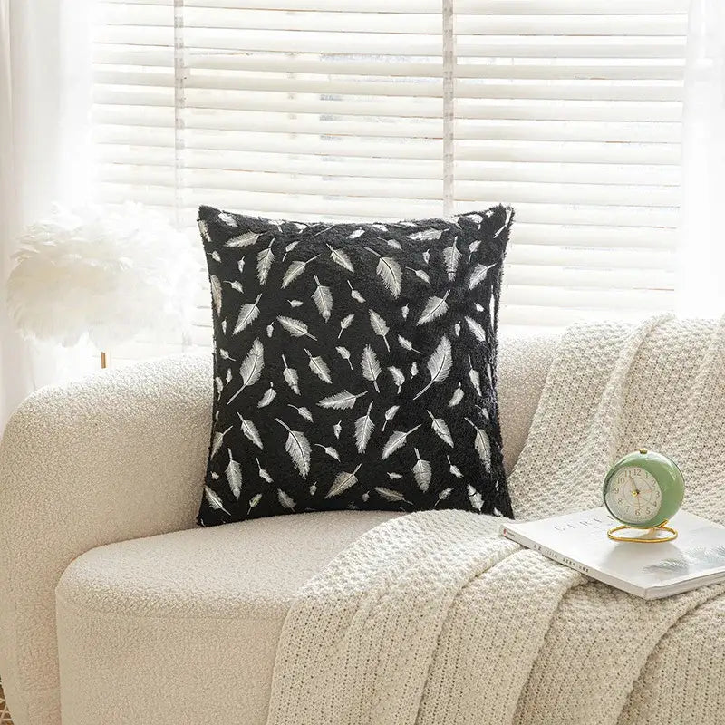 Black throw pillow with white feather style pattern and plush textured fabric for bronzed feather style decor