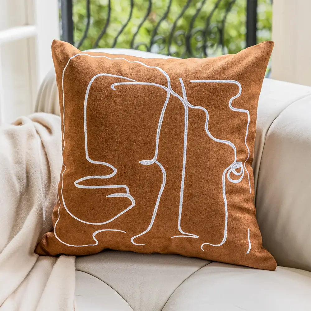 Brown suede plush cushion cover with white geometric embroidery of abstract faces for living room decor