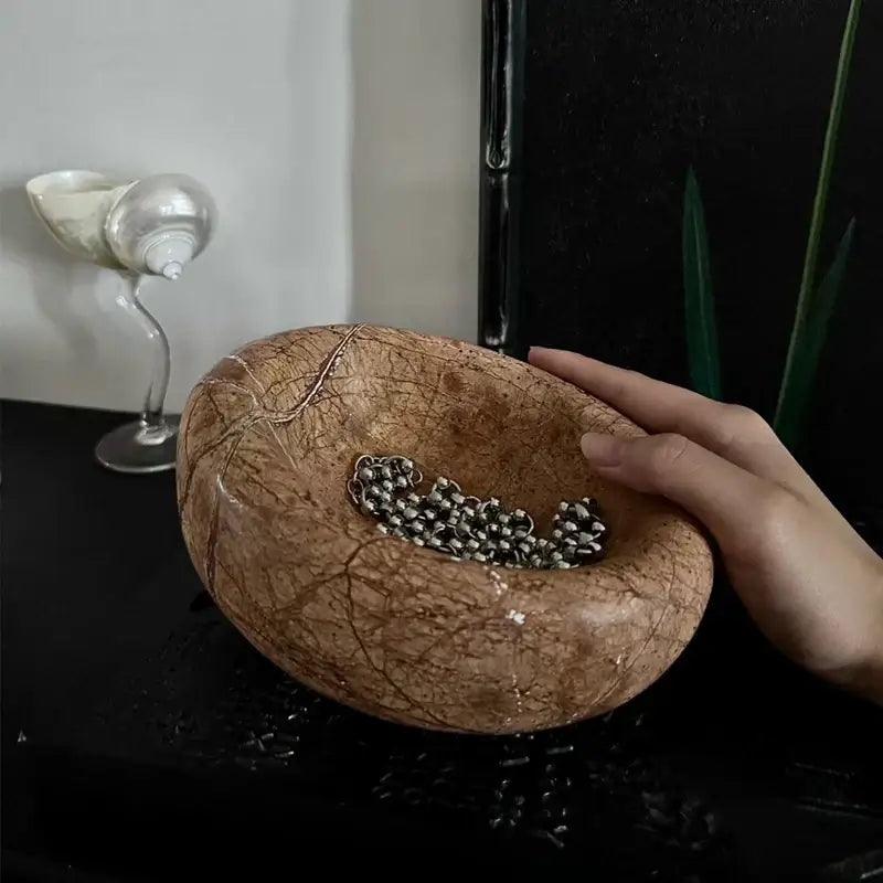 Brown and gray nest marble bowl with rustic brown coconut shell holding silver beads for bedroom jewelry storage