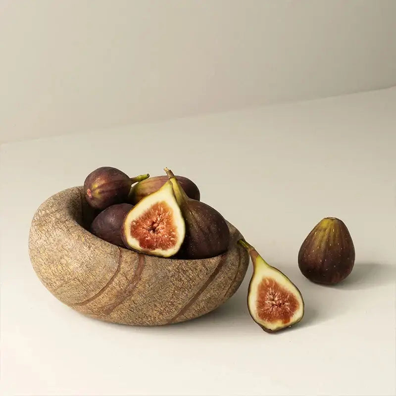 A brown and gray nest marble bowl featuring a rustic wooden bowl with dark purple figs for bedroom jewelry storage
