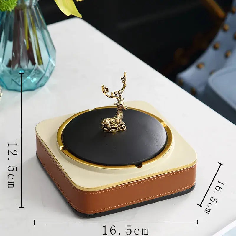 Brown leather desktop storage basket with a gold deer figurine and a square ashtray with beige and black trim