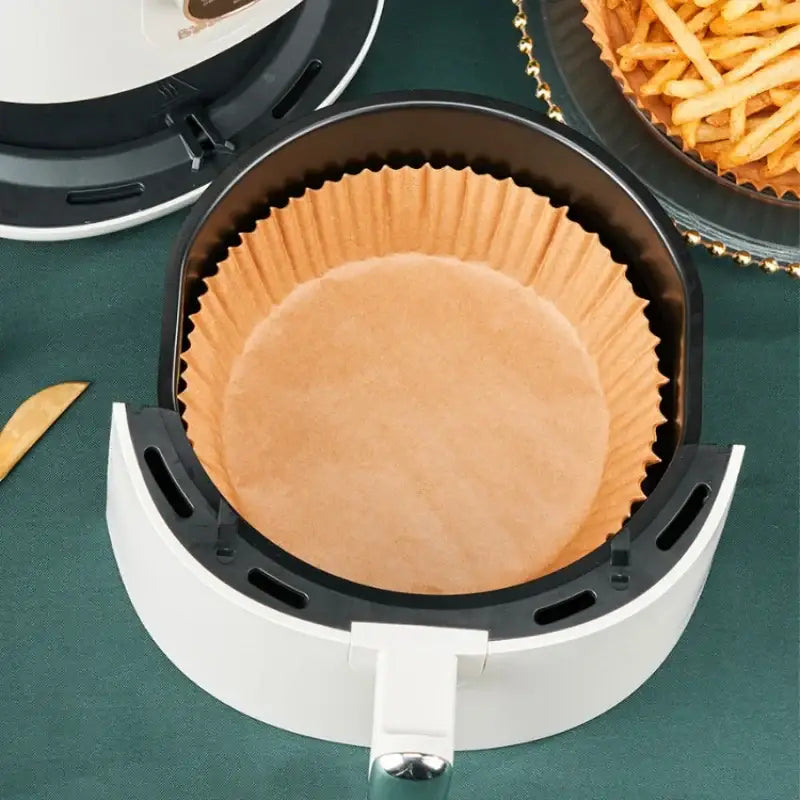Brown non-stick barbecue paper liner inside a white air fryer basket for kitchen cooking and baking use