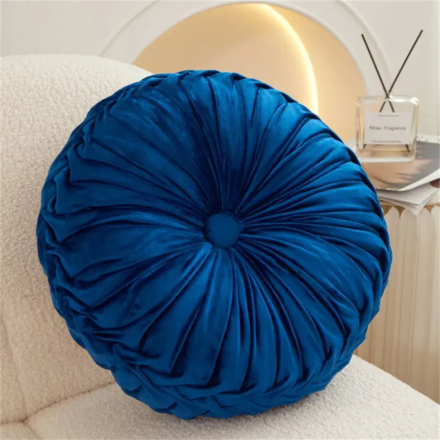 A plush deep blue velvet round seat cushion with gathered center design for living room use