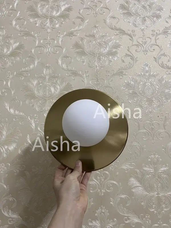 Brushed brass circular wall lamp with a gold-toned finish and smooth white frosted glass shade for bedroom decorbites circular wall
