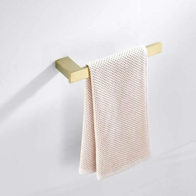 A cream towel with woven mesh hangs from a brushed gold stainless steel wall-mounted rack in the decorbites set