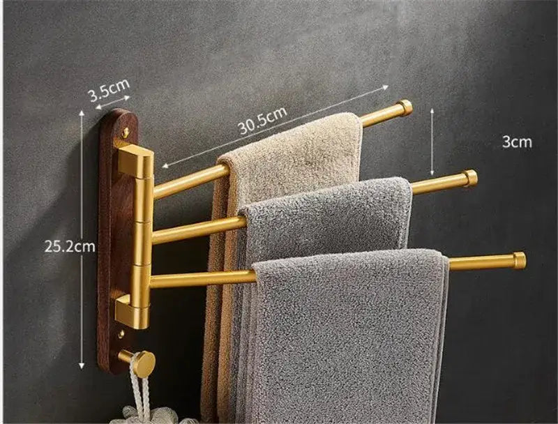 Brushed gold swivel towel hanger with dark wood base holding three beige and gray towels for bathroom use