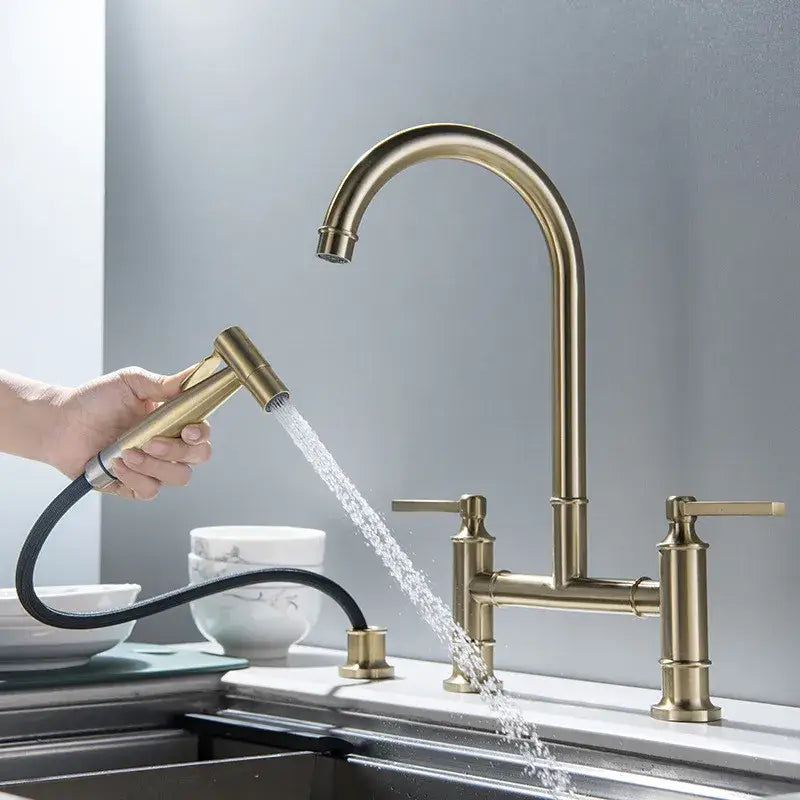 Brushed gold kitchen bridge faucet with hand shower head brass-colored curved spout and two handles