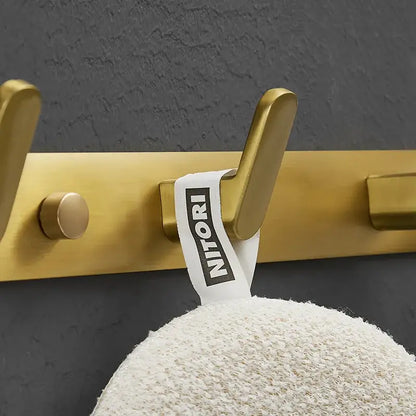 Brushed gold metal robe hook with white Nitori brand tag for bathroom and kitchen decorbites brushed gold hardware