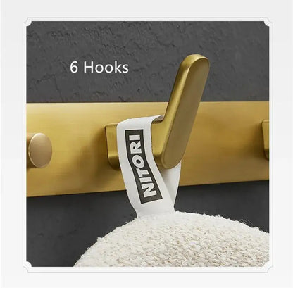 Brushed gold robe hook with sleek modern metal design and Nitori brand label for bathroom and kitchen decorbites brushed gold