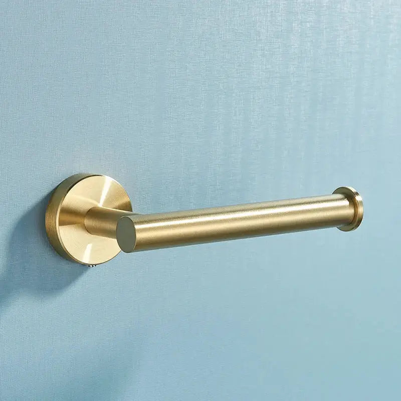 Brass-finished toilet paper holder with cylindrical design and circular base in brushed gold stainless steel bathroom accessories set