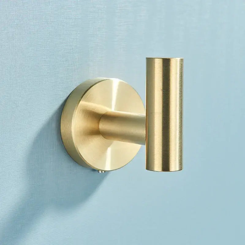 Brass-finished wall-mounted hook with circular base and cylindrical arm from brushed gold stainless steel bathroom accessories set