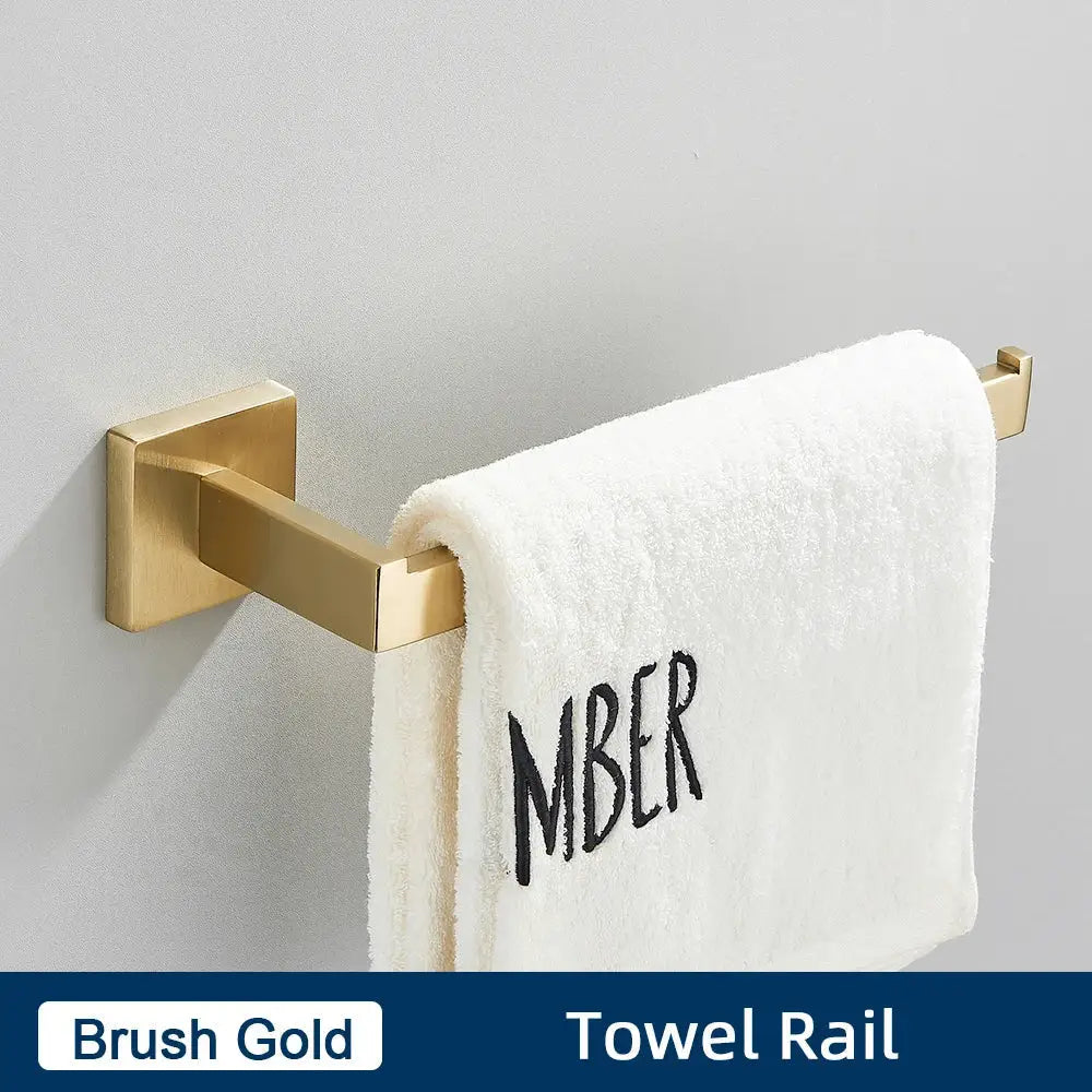 Brushed gold stainless steel towel rail holding a white towel with black embroidered lettering in bathroom accessories set