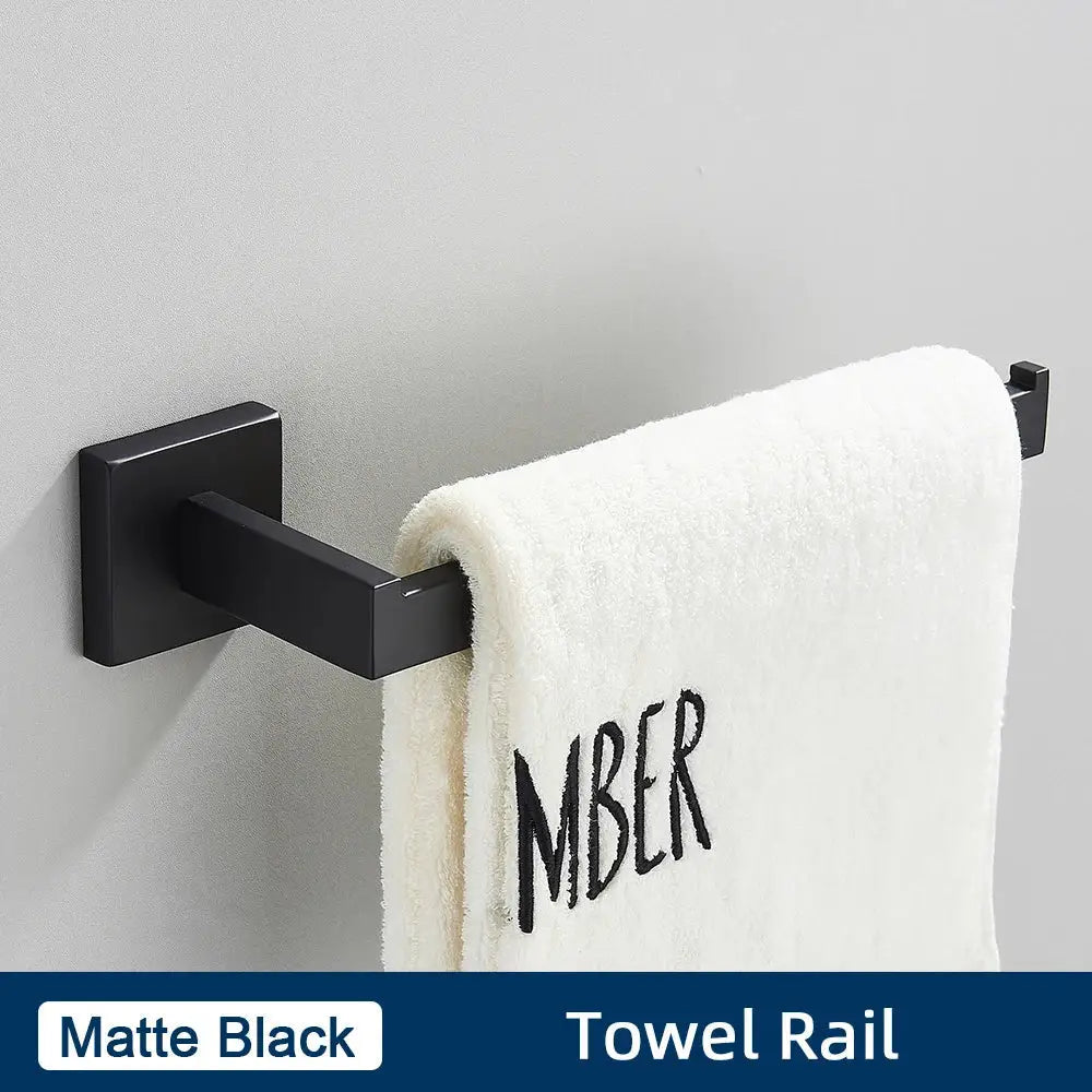 Matte black towel rail holding a white towel with amber embroidery in a brushed gold stainless steel bathroom accessories set