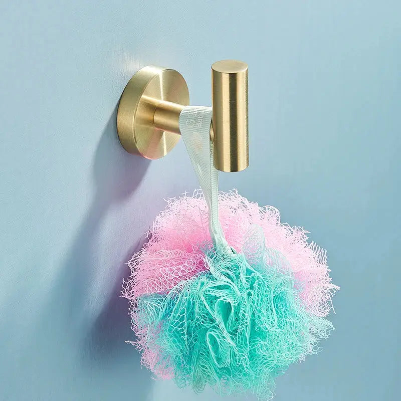 Brushed gold stainless steel bathroom accessories set with pastel pink and teal two-toned loofah hanging on wall hook