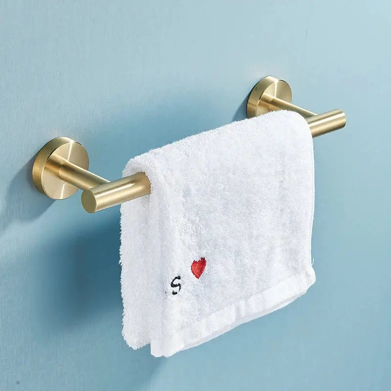Gold-toned brushed stainless steel double towel rack holding white terry cloth towel with embroidered red heart for bathroom accessories set
