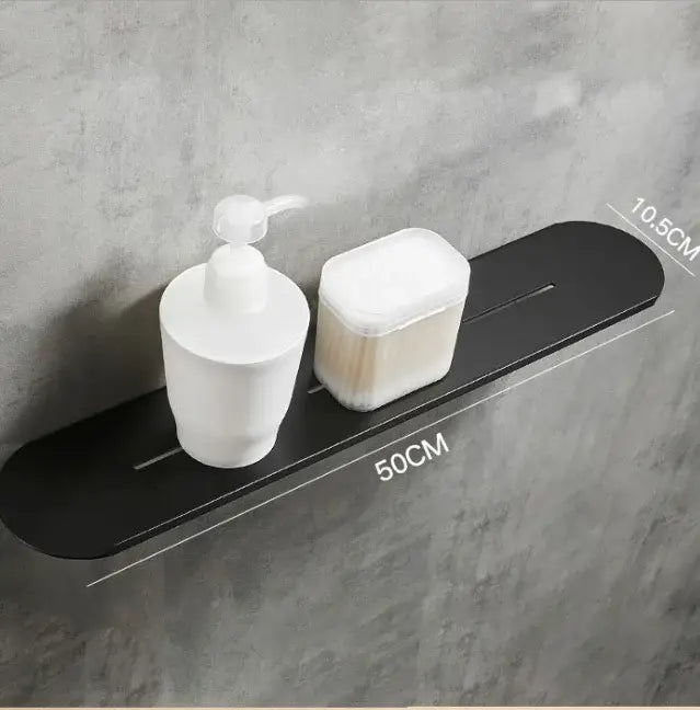 Brushed gold stainless steel bathroom storage rack with mirror front beside black matte wall-mounted shelf holding soap dispenser and cotton swabs