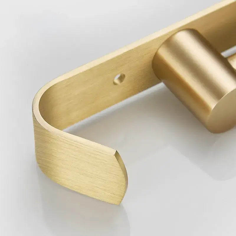 Brass-finished modern toilet paper holder with sleek curved design and brushed gold surface by decorbites brushed gold