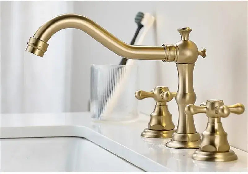 Antique brass-finished brushed gold basin faucet with three ornate cross handles and elegant curved spout by decorbites