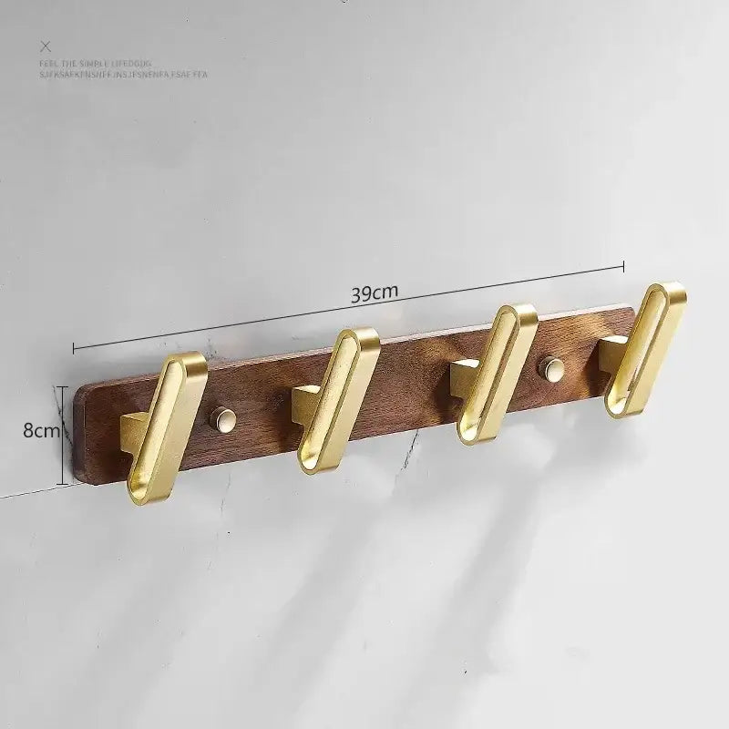 Brushed gold metal robe hook towel hanger mounted on dark wood plank with modern minimalist design for bathroom use
