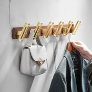 Brushed gold wood and aluminum robe hook towel hanger with metal hooks mounted on a wooden plank for hanging coats and bags