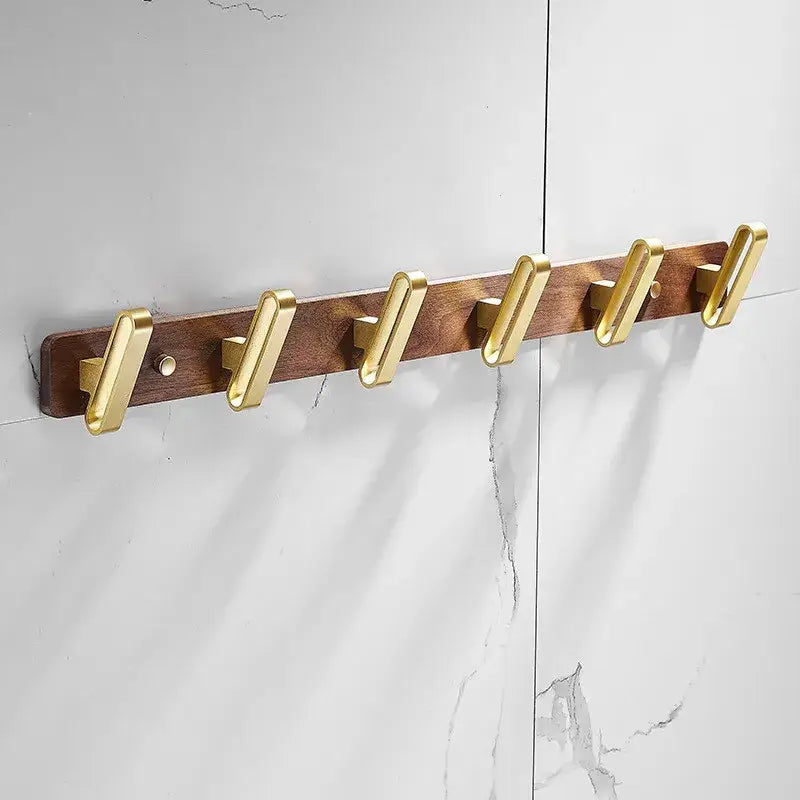 Brushed gold wood and aluminum robe hook towel hanger with gold-toned metal hooks on dark wood plank for bathroom use