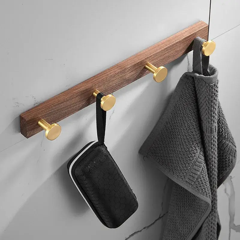 A sleek wooden hook towel hanger with three polished brushed gold aluminum robe hooks for bathroom use