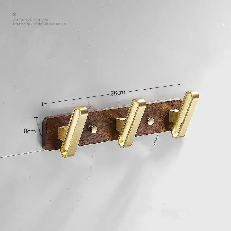 Gold-toned brushed metal robe hook towel hanger mounted on dark wood plank for bathroom use