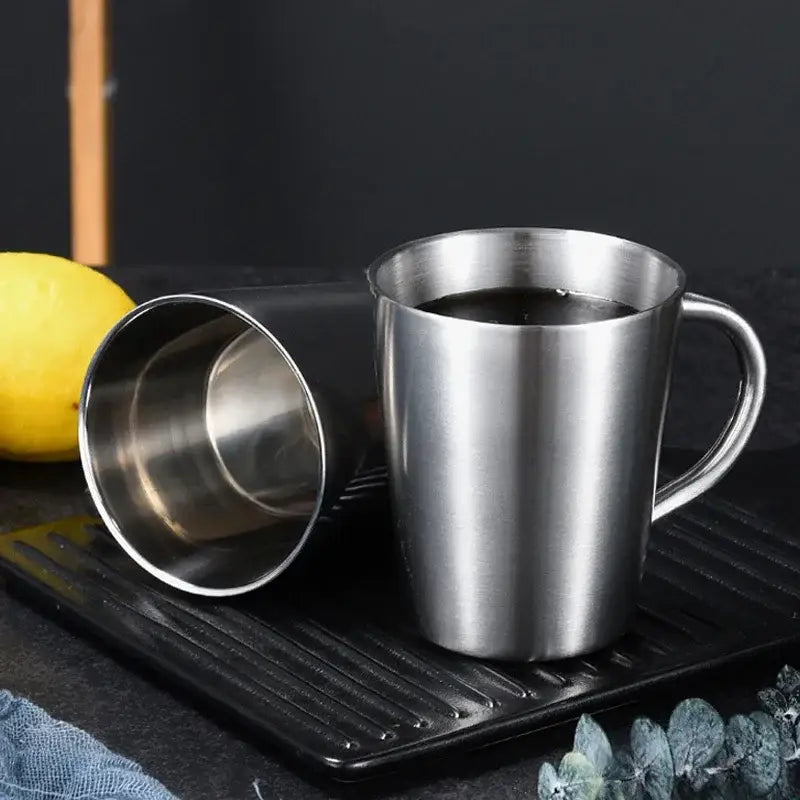 Shiny silver stainless steel thermal mug with a sleek cylindrical body and curved handle for kitchen drinkware