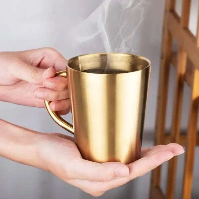 Gold-colored stainless steel thermal mug with sleek cylindrical design and curved handle from brushed metallic drinkware set