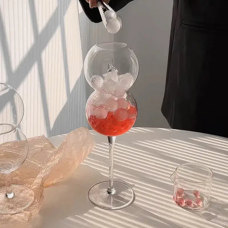 A decorbites bubble ball glass set features a clear double-globed wine glass with red liquid and ice cubes